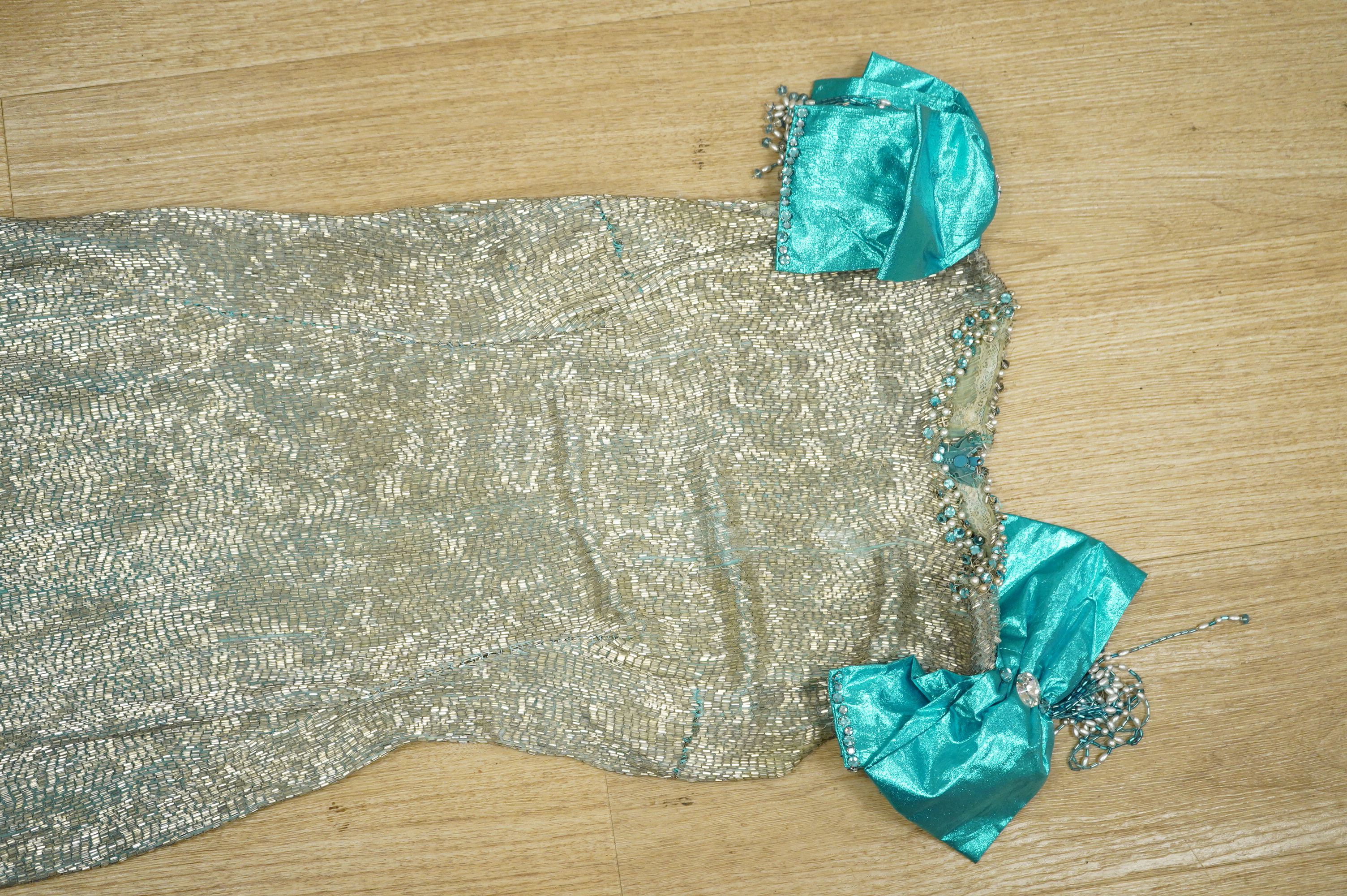 A graduated beaded turquoise and silver bugle beaded evening dress, with large turquoise metalic bows at the shoulders with diamonte, pearl and bead tassel decoration, bust front 39cm, length 127cm